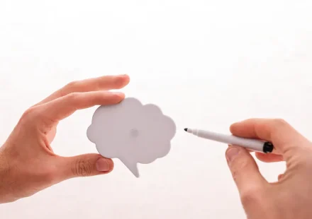 Hands holding and pointing at a speech bubble cutout
