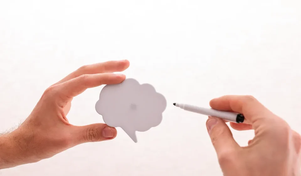 Hands holding and pointing at a speech bubble cutout
