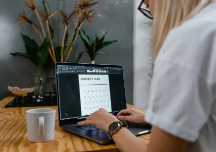 Person using laptop with a content plan calendar on screen