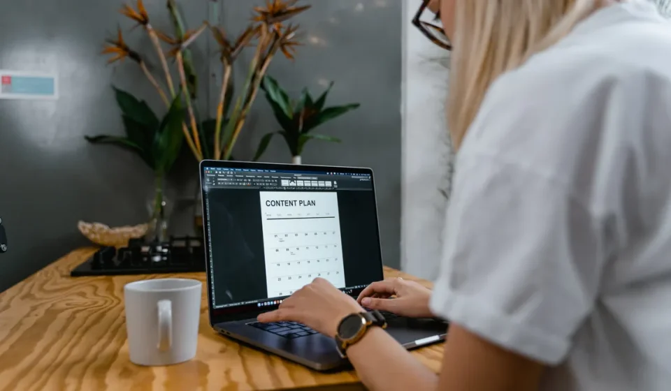 Person using laptop with a content plan calendar on screen