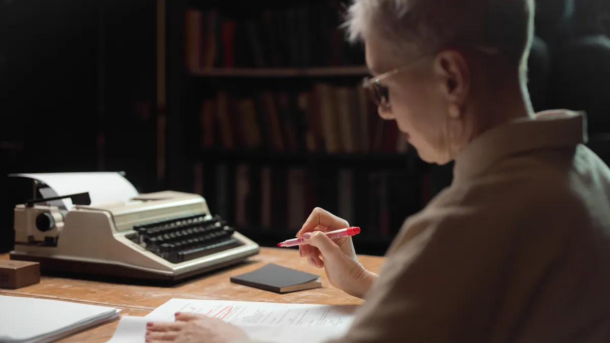 How to edit AI-written SEO drafts for brand voice Person annotating pages beside a typewriter