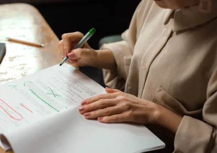 Person editing printed draft with red and green markup