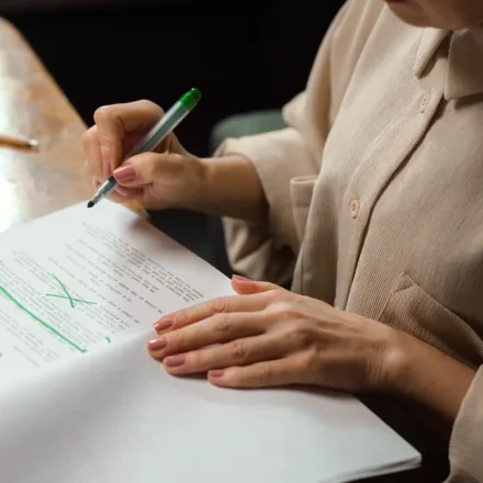 Person editing printed draft with red and green markup