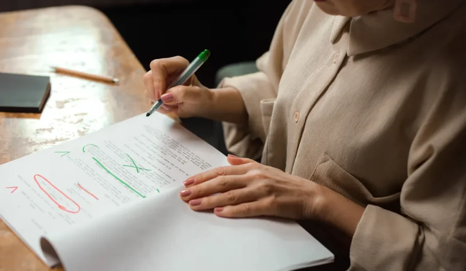 Person editing printed draft with red and green markup